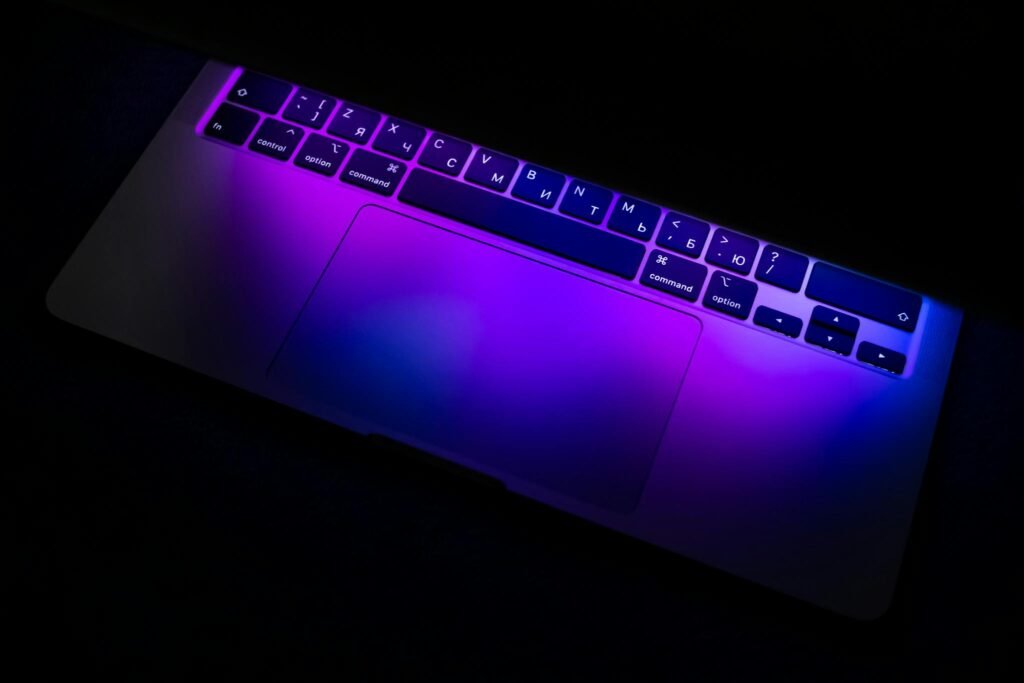 Neon-lit laptop keyboard with a purple glow creating a futuristic, tech-focused atmosphere.